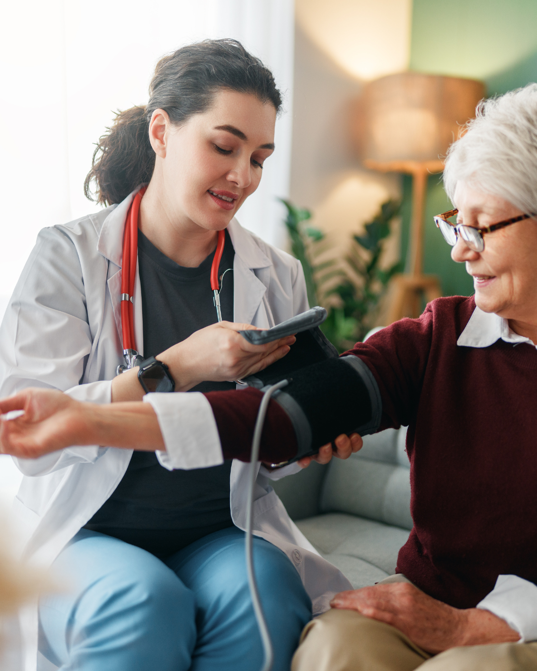 A nurse checking a resident's blood pressure in a warm, homelike room