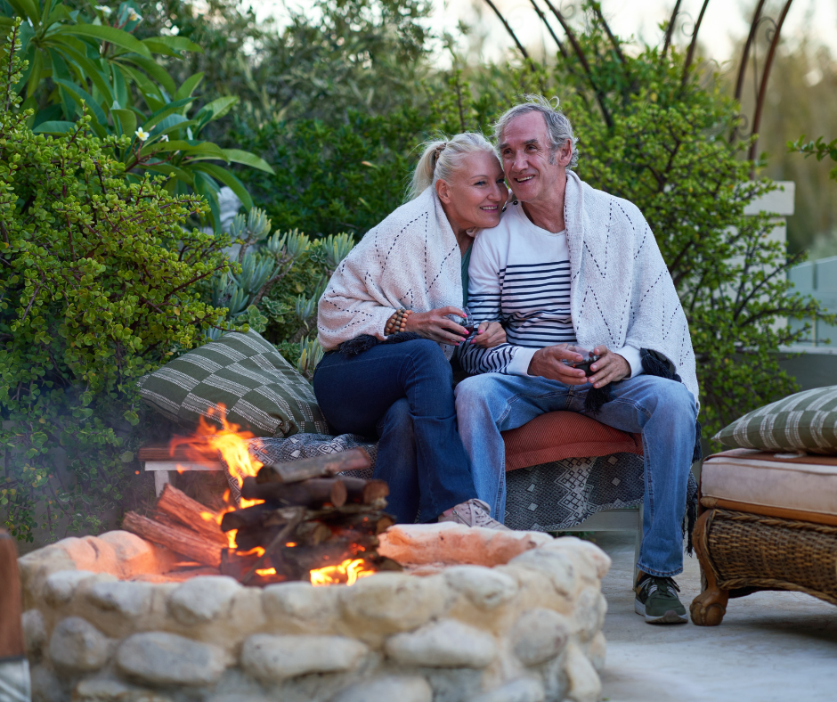 A senior couple relaxing by an outdoor firepit at dusk