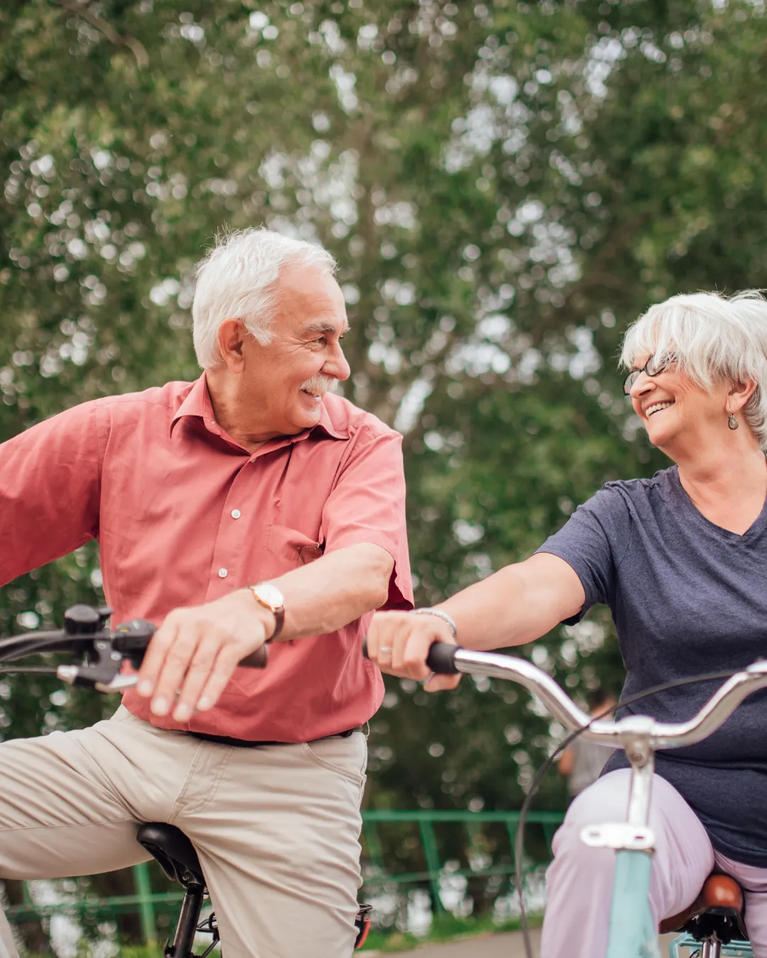 A senior couple riding bicycles in a park