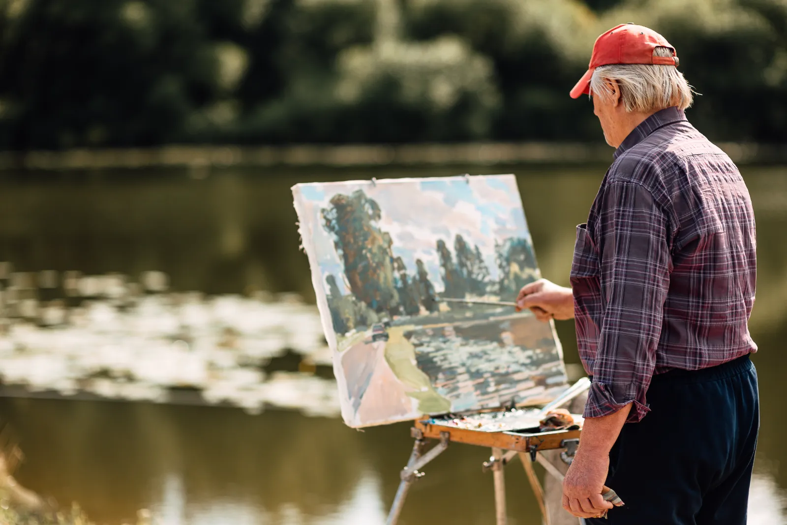 A resident painting a landscape at the water's edge