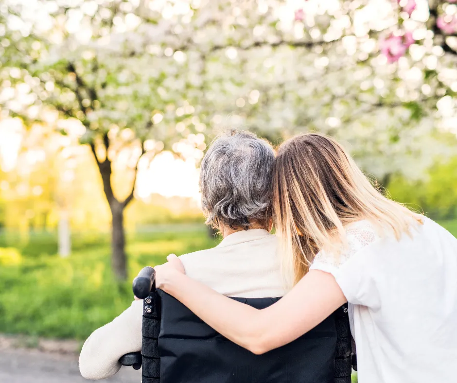 A caregiver and resident sharing a quiet moment beneath blossoming trees