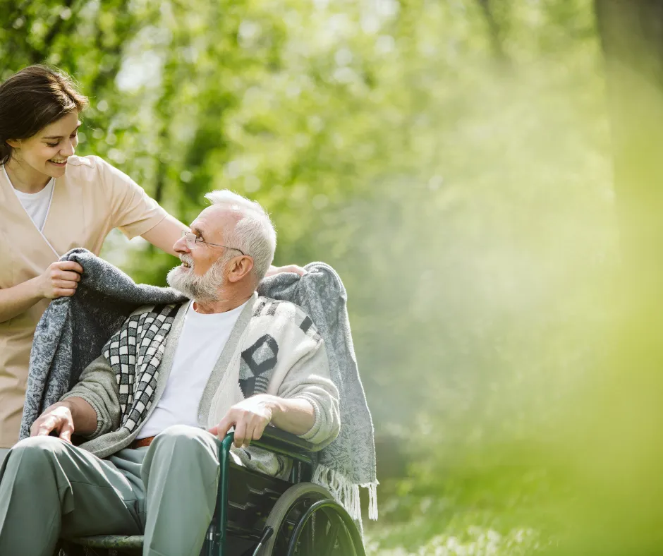 A caregiver wrapping a soft blanket around a resident in the garden
