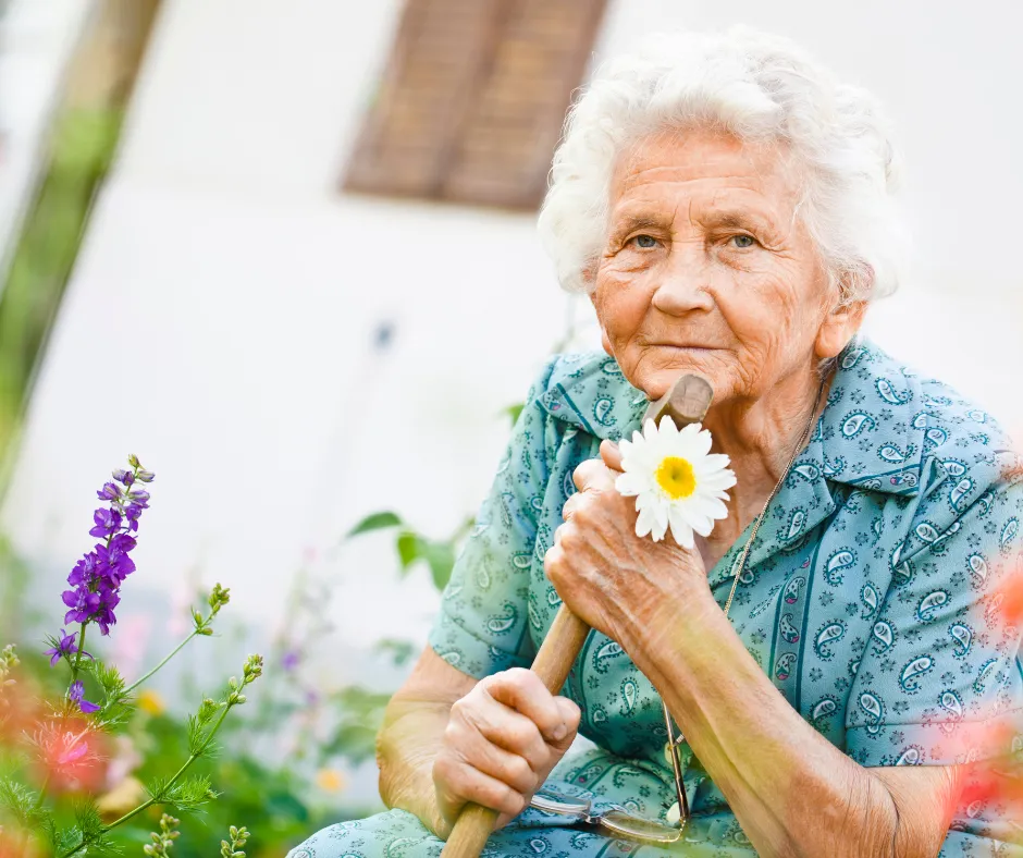 A resident holding a daisy in the garden