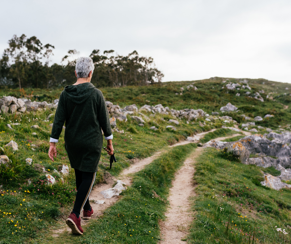 A woman walking a scenic trail through rolling green hills