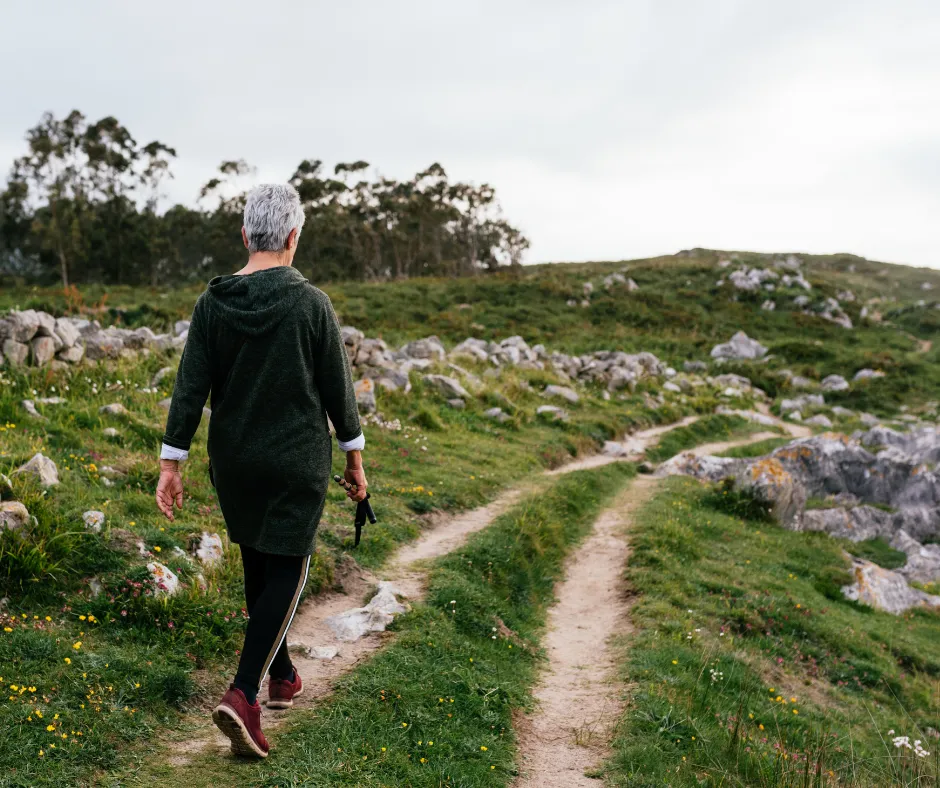 A woman walking a scenic trail through rolling green hills