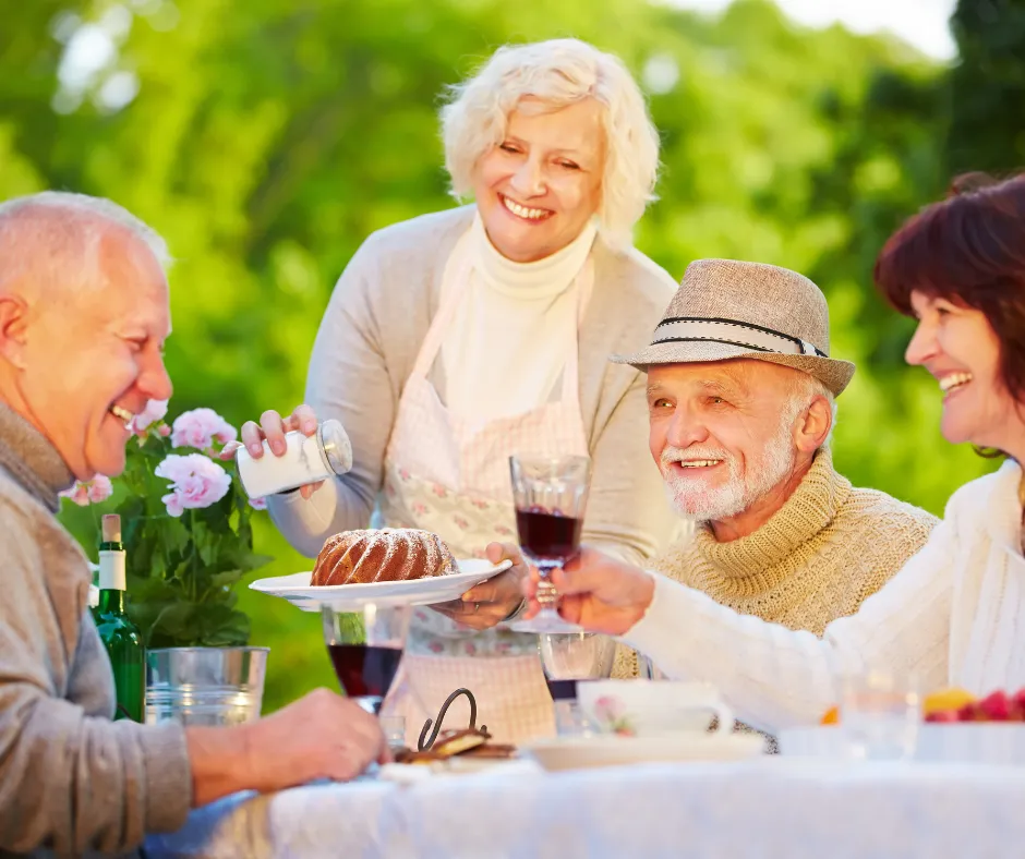 Friends enjoying cake and wine together at an outdoor garden table