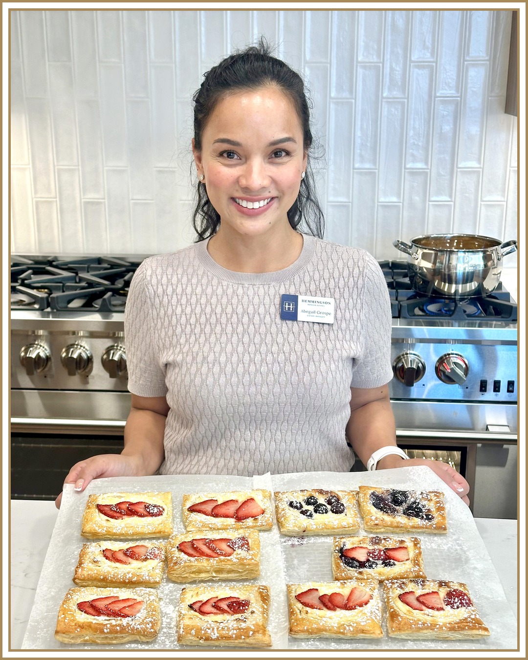 Abegail, Dietary Manager at Hemmingson Senior Living in Coeur d'Alene, holding a tray of fresh strawberry and blueberry pastries