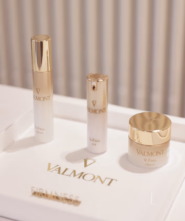 Three Valmont V-Firm skincare products on a white tray with gold lettering reading firmness.