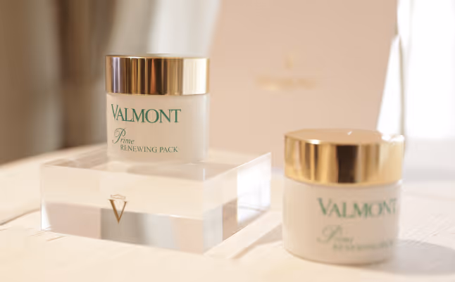 Two Valmont Prime Renewing Pack skincare jars with gold lids on a light surface.