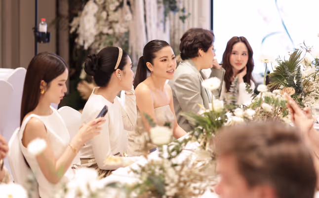 Group of people seated at a decorated table engaged in conversation at an event.
