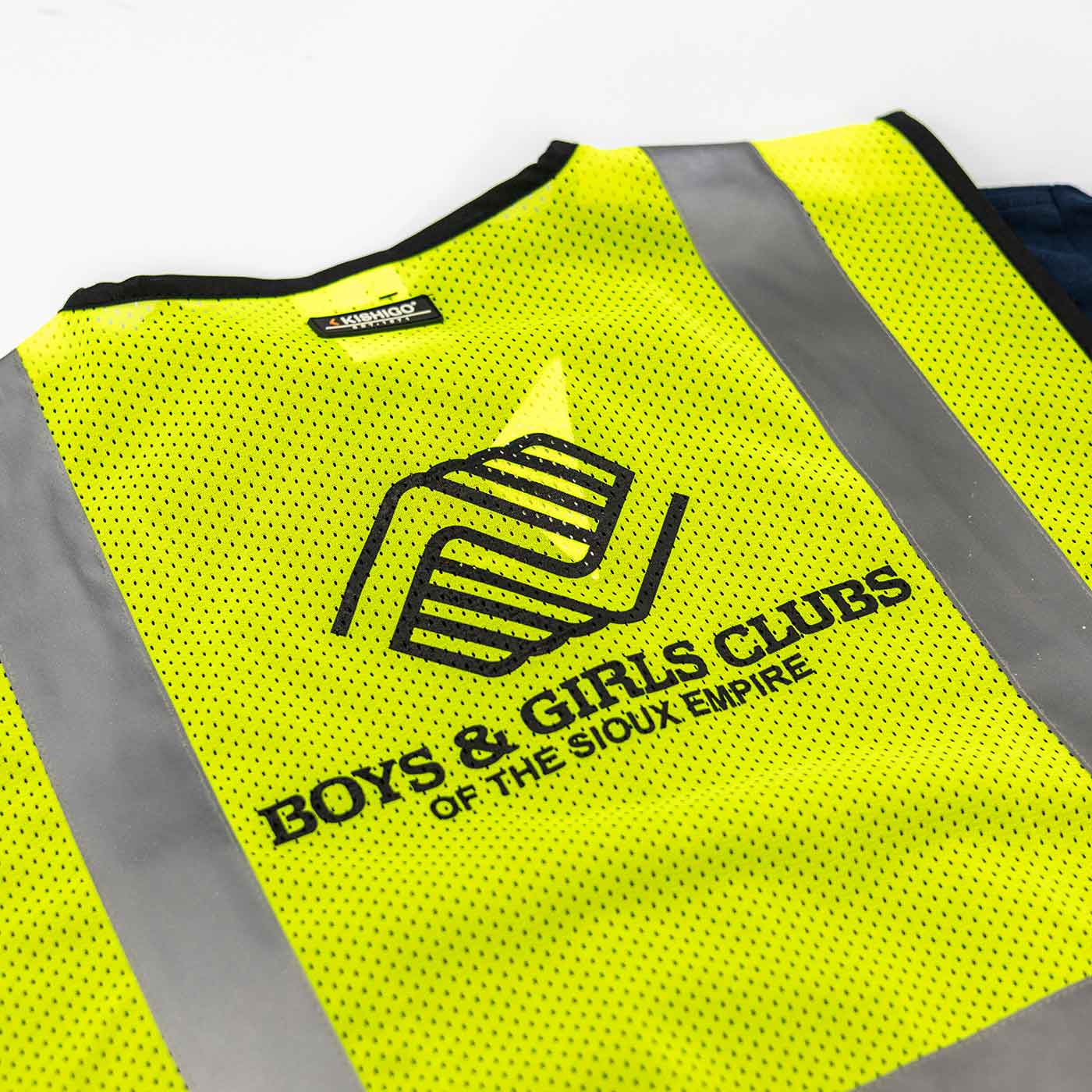 High-visibility yellow safety vest with reflective gray stripes and black logo and text reading 'Boys & Girls Clubs of the Sioux Empire'.