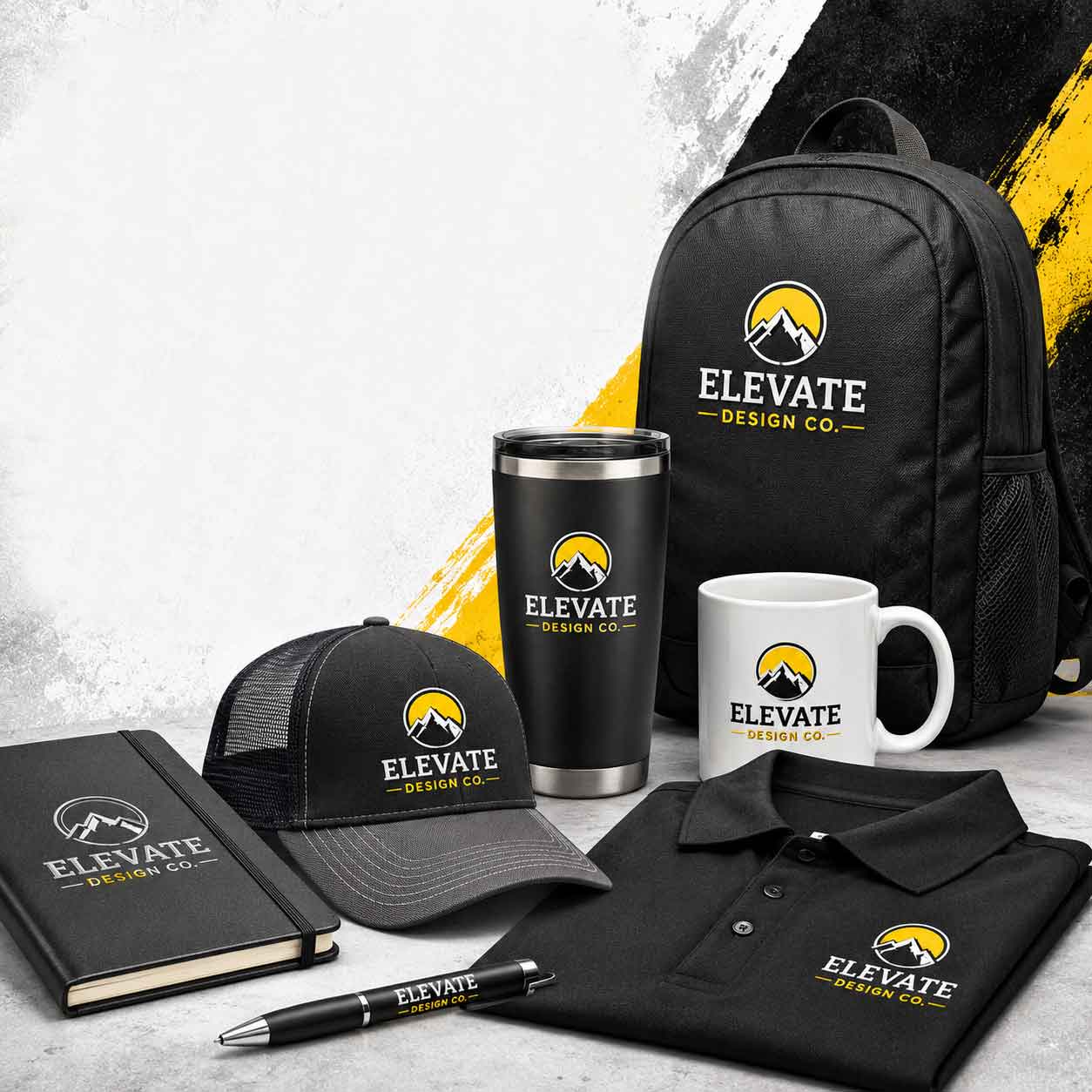 Collection of branded promotional items including a black backpack, black and gray cap, black travel tumbler, white ceramic mug, black polo shirt, black notebook, and black pen, all featuring the Elevate Design Co. logo with a yellow sun and white mountain graphic.
