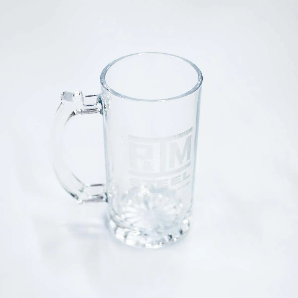 Empty clear glass beer mug with a handle on a white surface.