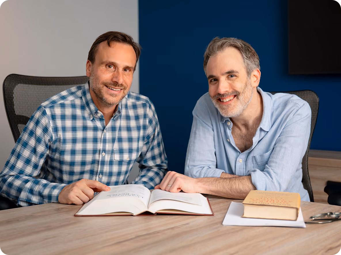 Brian Kohn & Ian Dumain reading book in office conference room