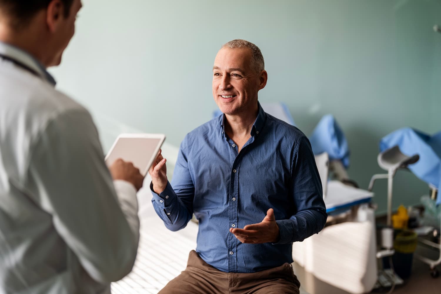 In a hospital room, a man speaks with a doctor about his health and medical advice.