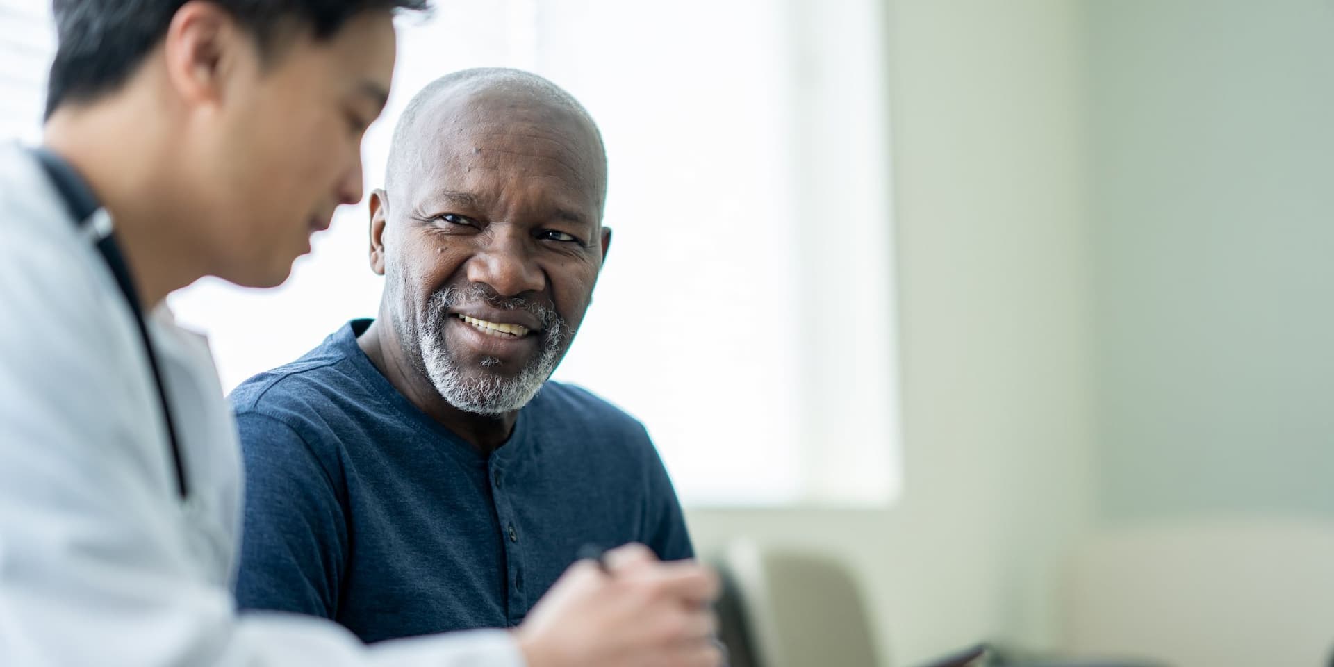 A man converses with a doctor in a medical setting, discussing health-related matters.