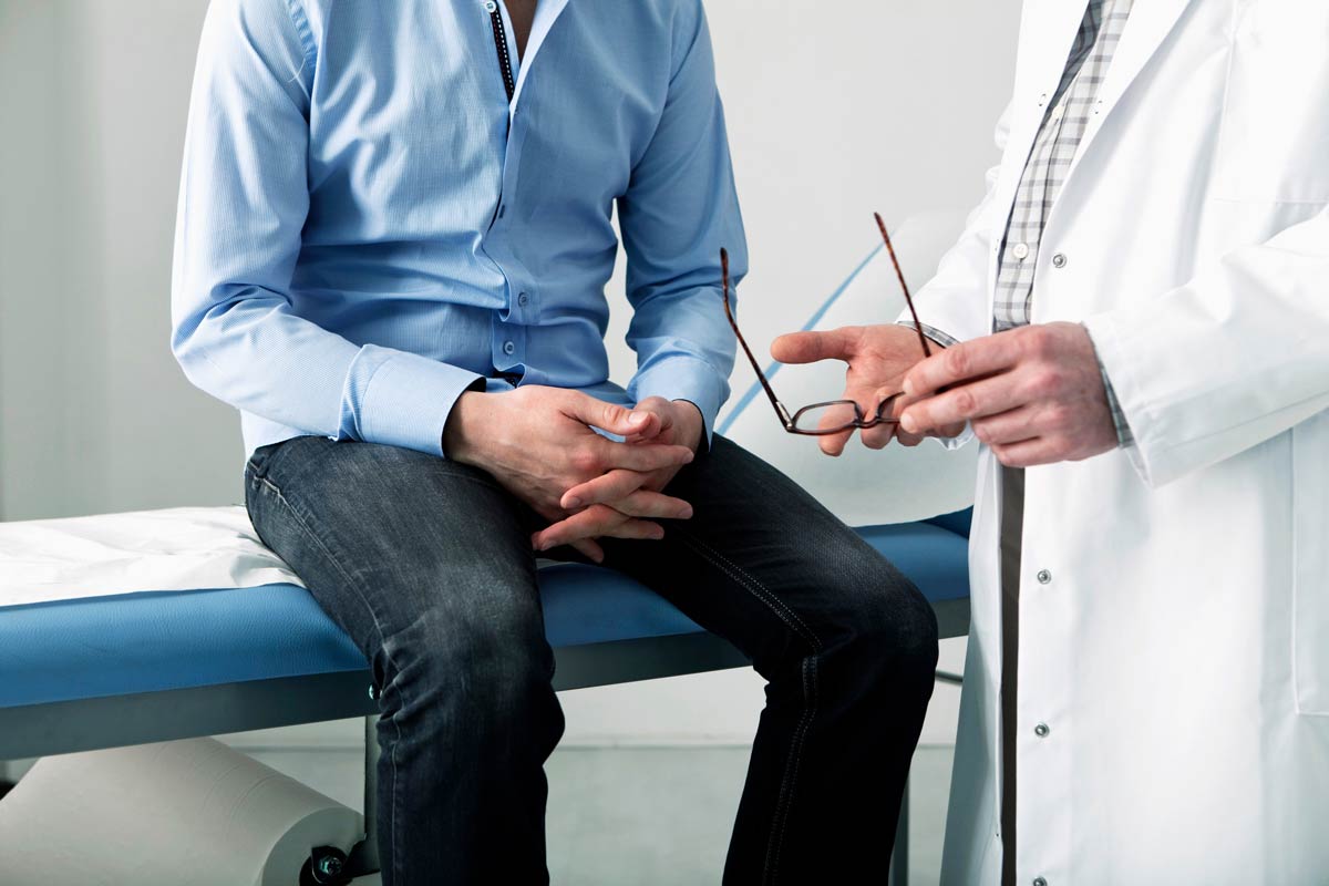 Man consulting with doctor about erectile dysfunction symptoms during medical visit.