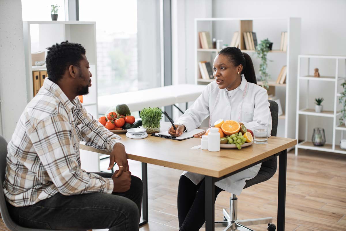 Doctor advising patient on diet and lifestyle for natural erectile dysfunction treatment during consultation.