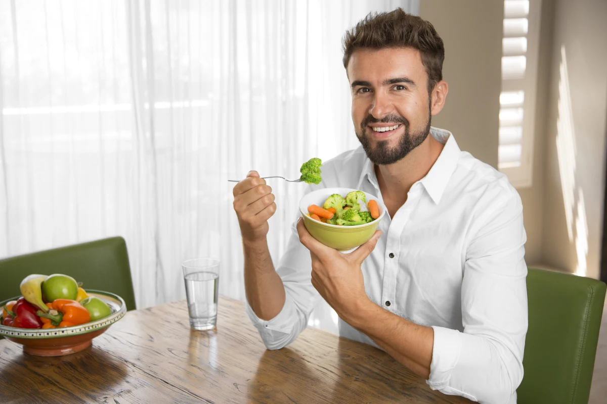 Man eating a healthy salad at home to support erectile strength and overall wellness.