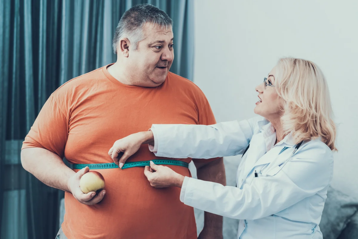 Doctor discussing belly fat causes in men and low testosterone while reviewing healthy nutrition and metabolism management strategies.