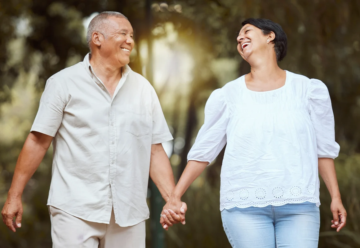 Older couple smiling and holding hands outdoors, representing the benefits of testosterone therapy for men in supporting energy, vitality, and quality of life.