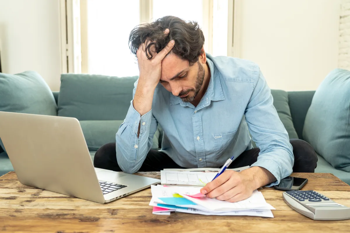 Man sitting at a desk looking stressed and fatigued, representing the lifestyle and health factors that cause low testosterone levels in men.