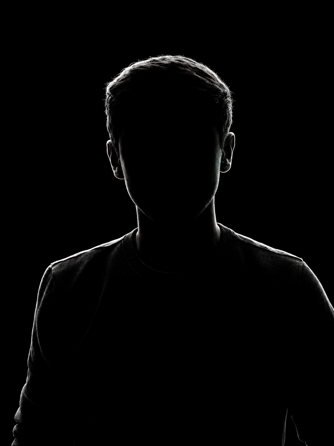 Silhouette of a person against a black background with light outlining hair and shoulders.