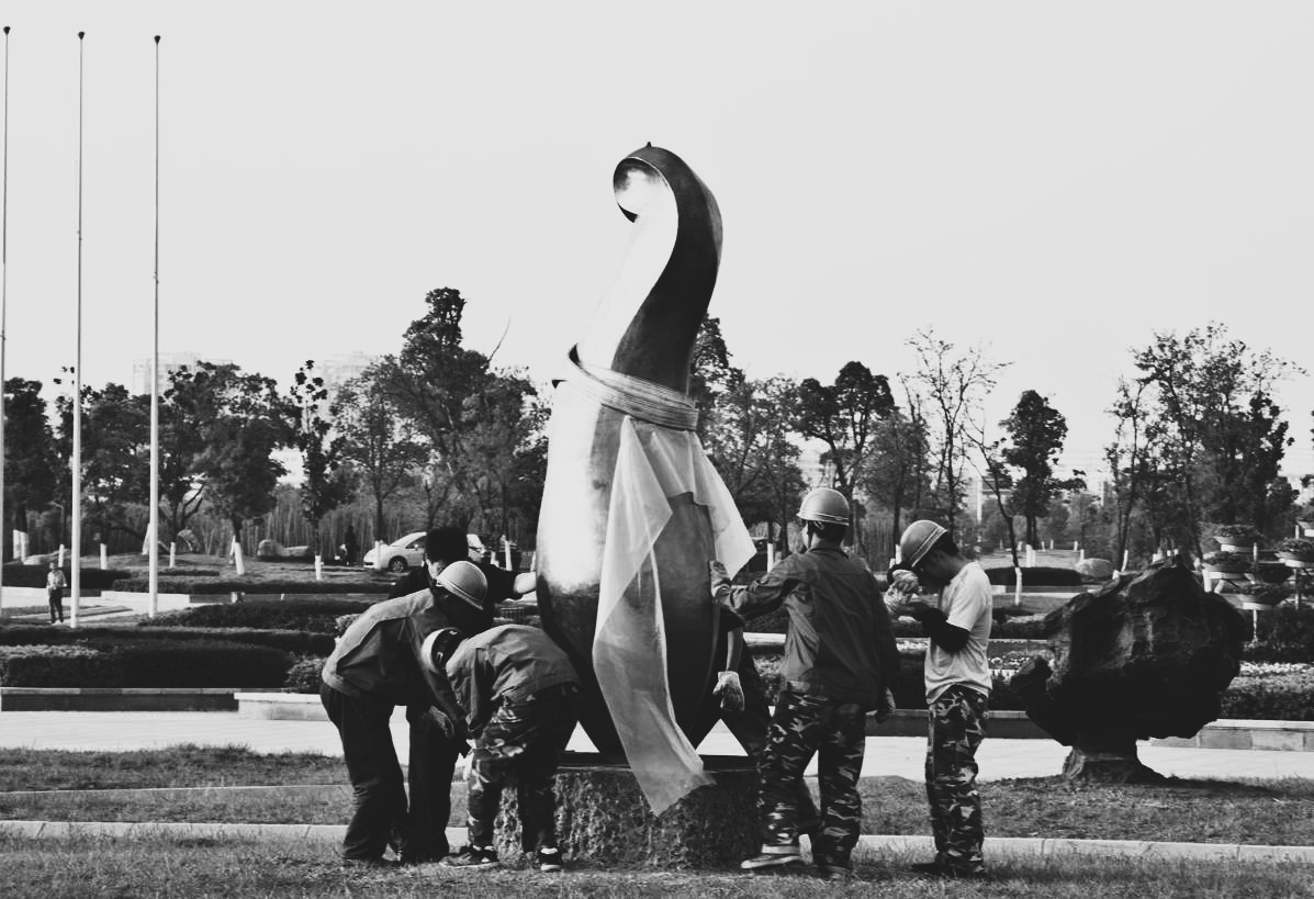 Team members positioning Woman with Umbrella during installation.
