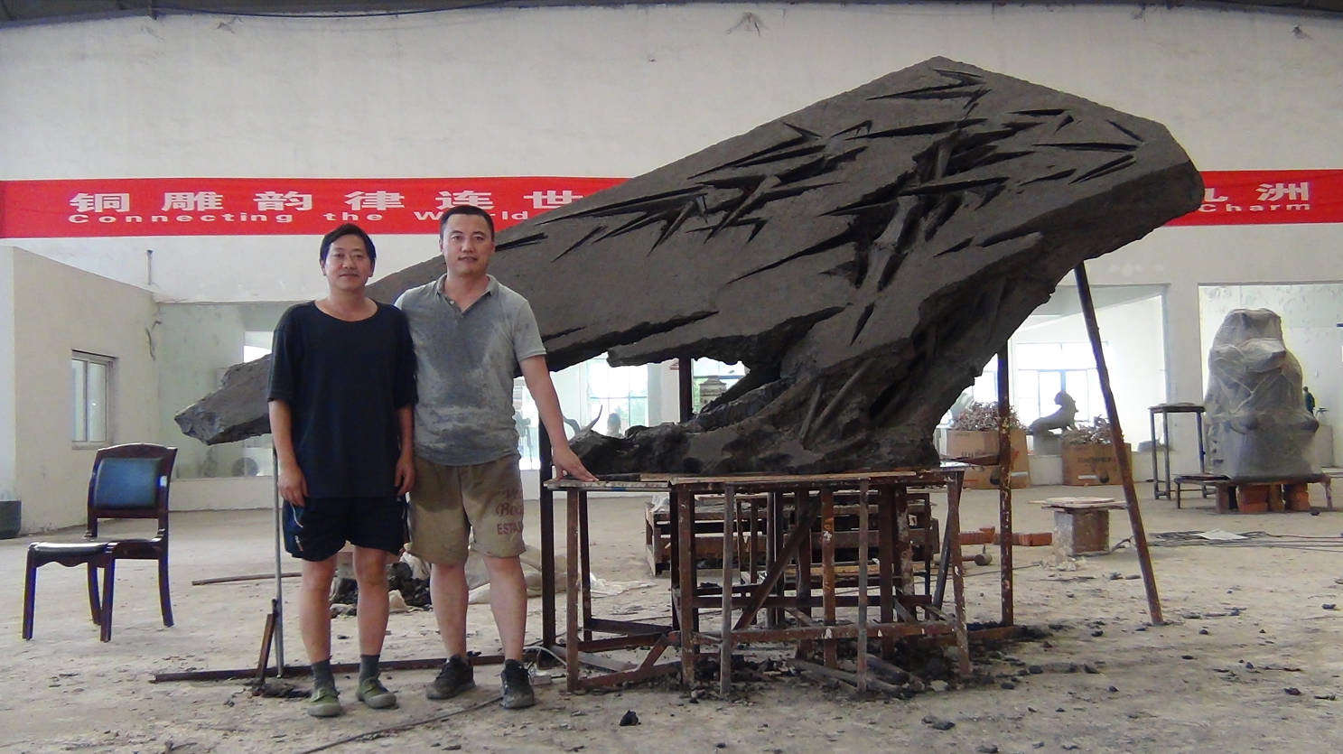Two people beside Bamboo in Wind in the workshop.