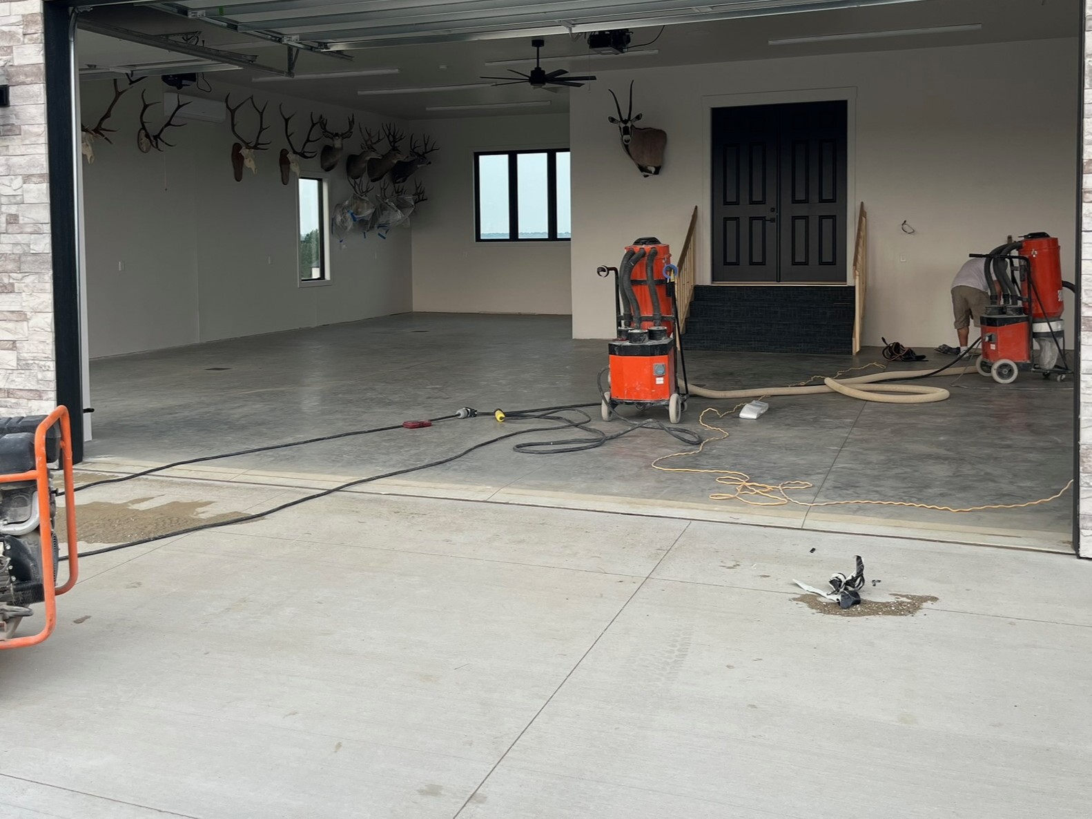 Large garage with professionally prepared concrete floor, hunting trophy mounts on walls, and vacuum equipment inside. Step one for concrete coating installation