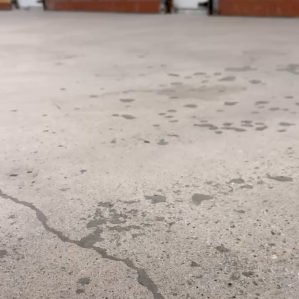 Pitting and surface deterioration on an unprotected garage floor concrete slab patched by Armour Floors