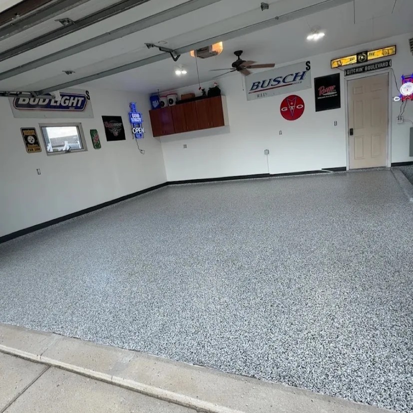 Clean garage with full broadcast professionally installed epoxy floor coating and beer brand signs on white walls.