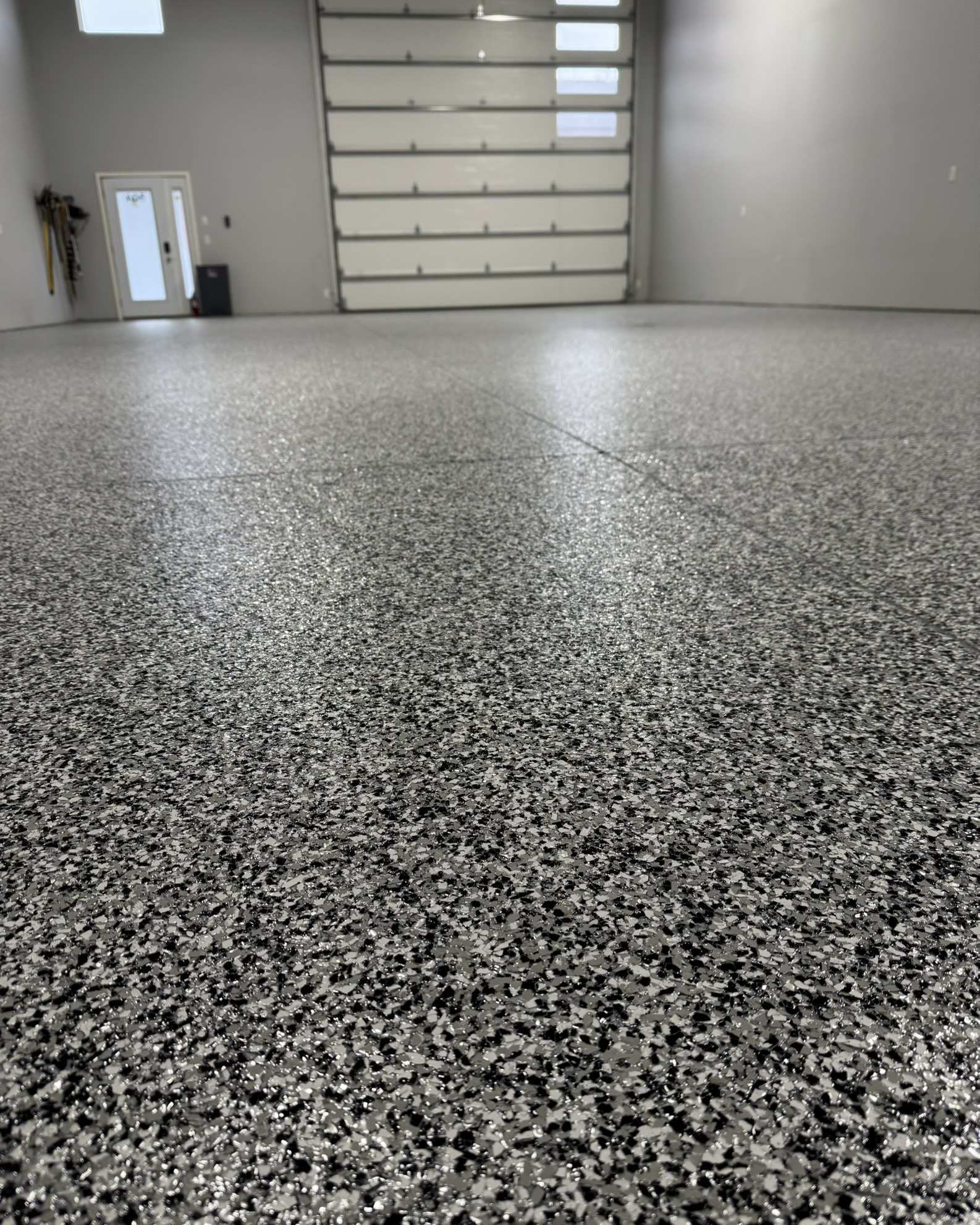 Finished shop with professional full broadcast flake epoxy floor and closed sectional garage door.