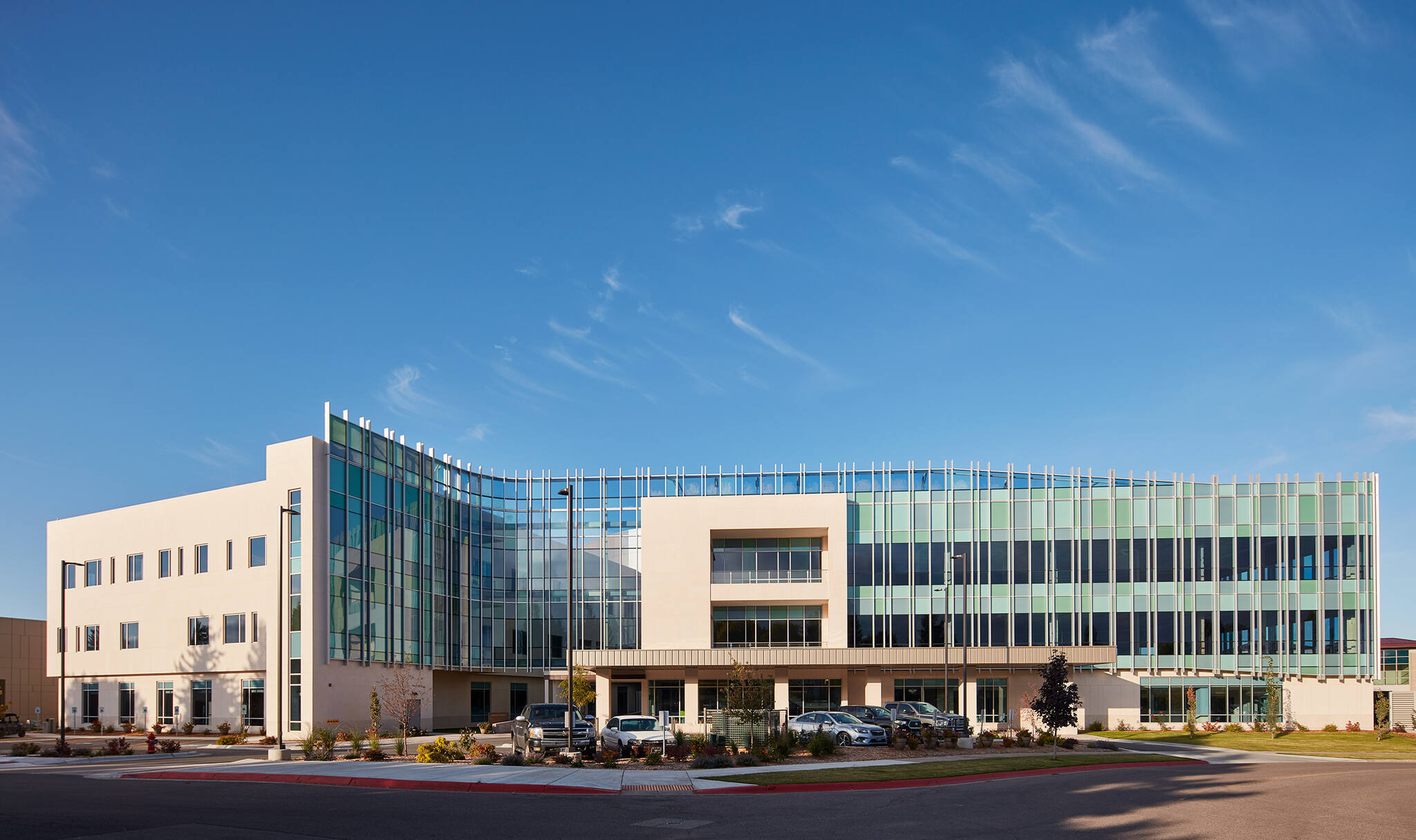Modern three-story office building with glass and beige exterior under a clear blue sky.