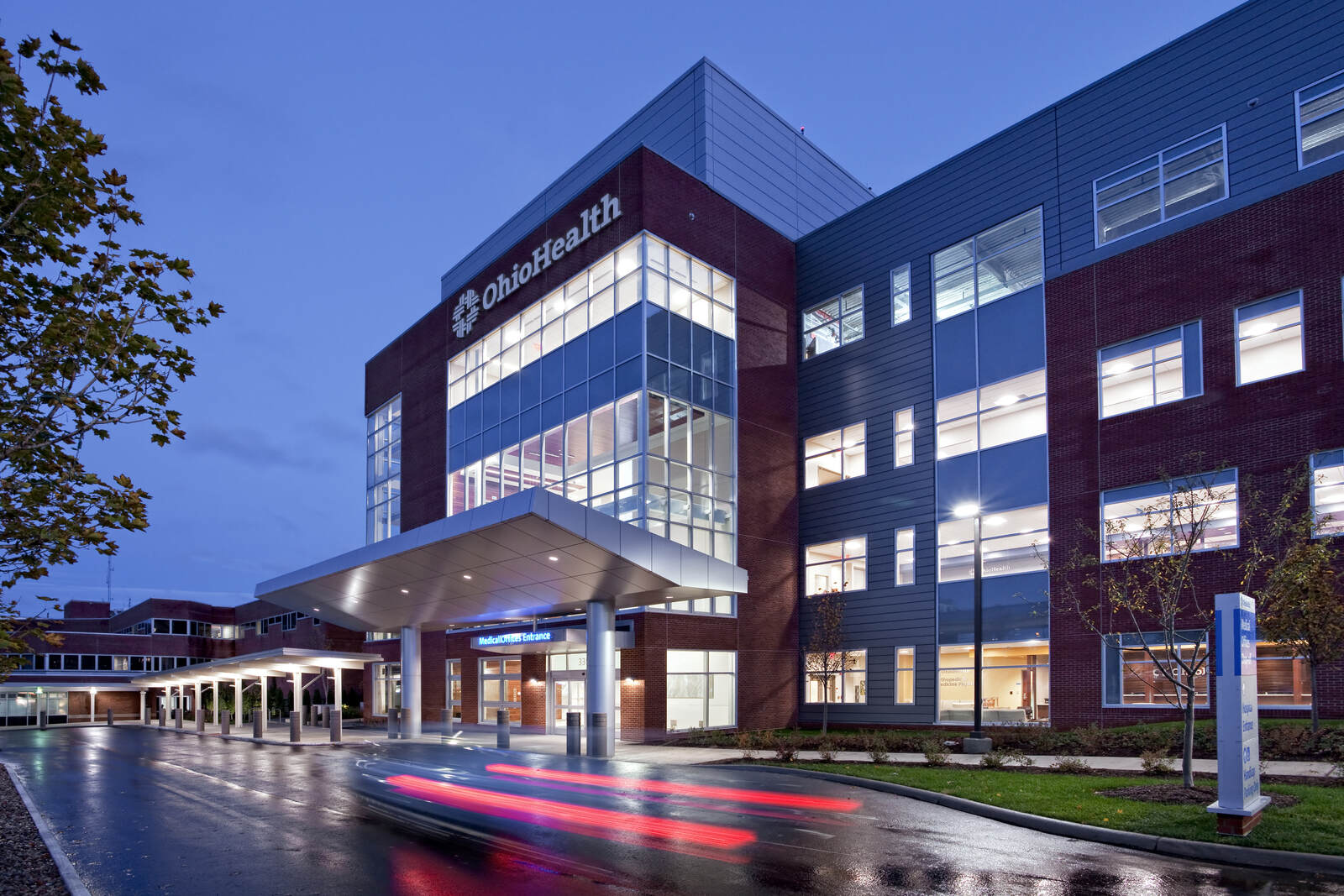 OhioHealth MedCentral building entrance during dusk with car light trails on wet driveway.