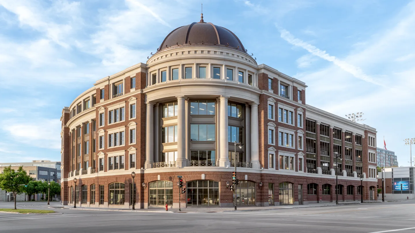Large classic public or academic building with brick facade and central dome under a blue sky.