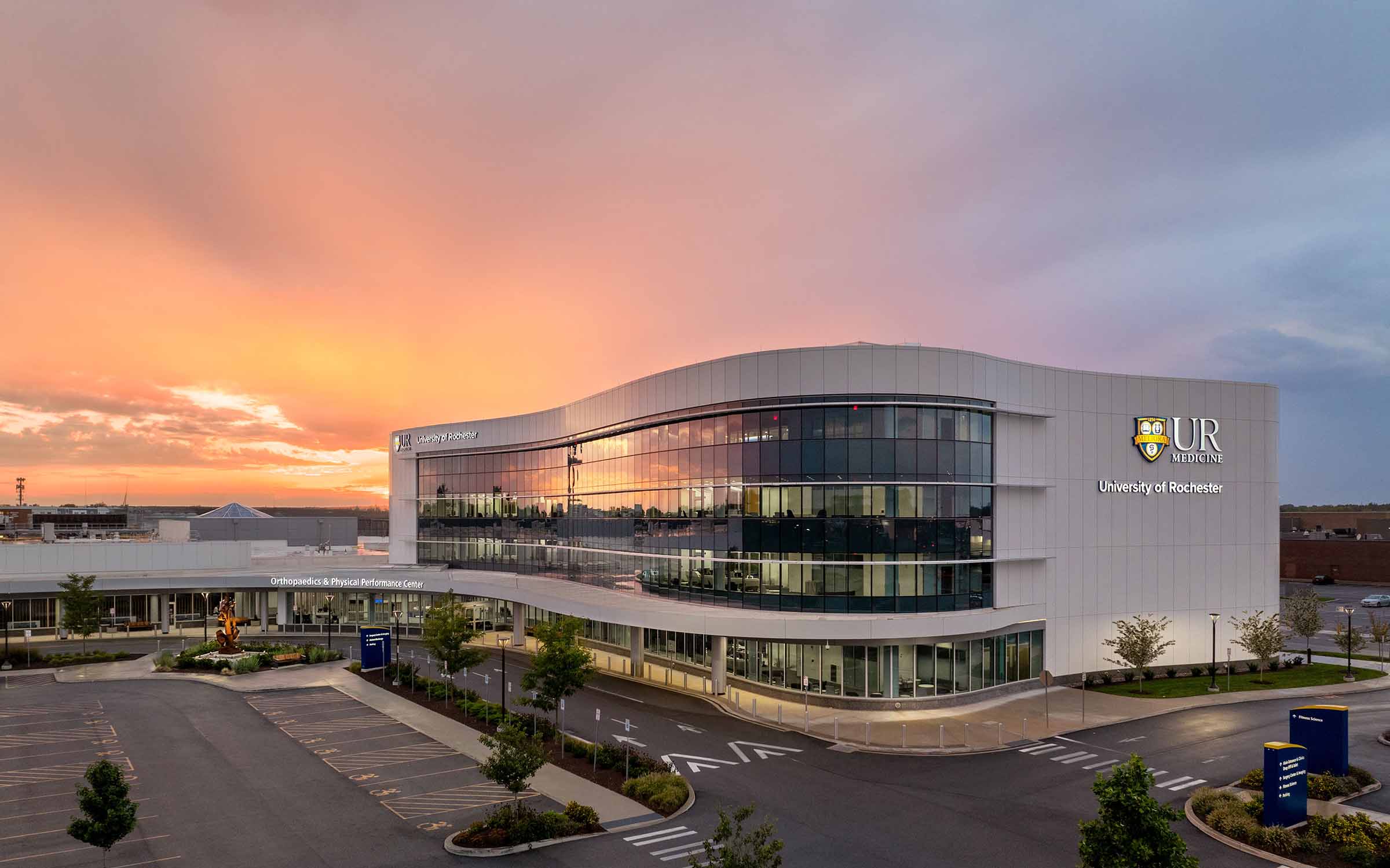 Modern University of Rochester Orthopaedic Center building at sunset with reflective glass facade.