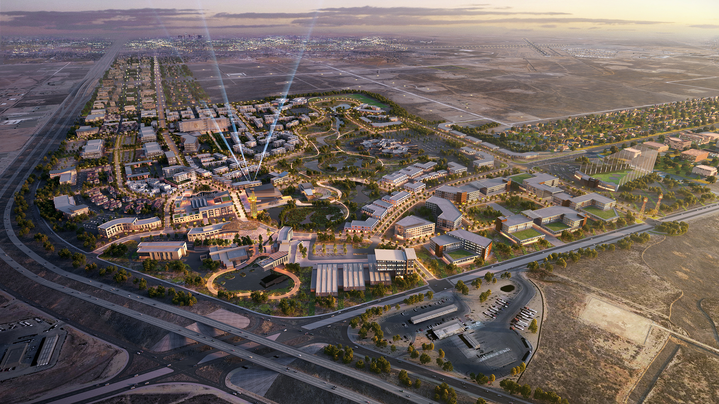 Aerial view of a planned suburban community with roads, buildings, green spaces, and highways at sunset.