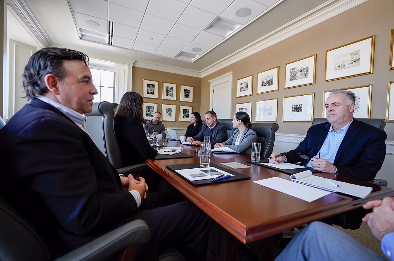Business team sitting around a conference table in a meeting room, discussing and taking notes.