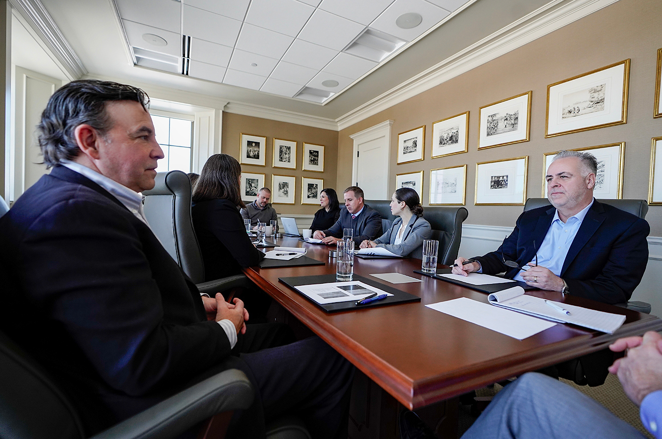 Business team sitting around a conference table in a meeting room, discussing and taking notes.