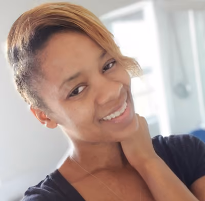 Smiling young woman with short blonde hair in a softly lit room.