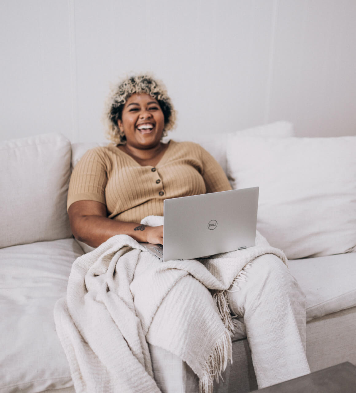 Woman smiling on couch with her laptop