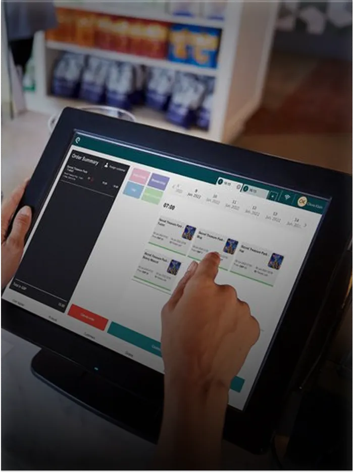 Person using a touchscreen POS system to select products in a store with shelves in the background.
