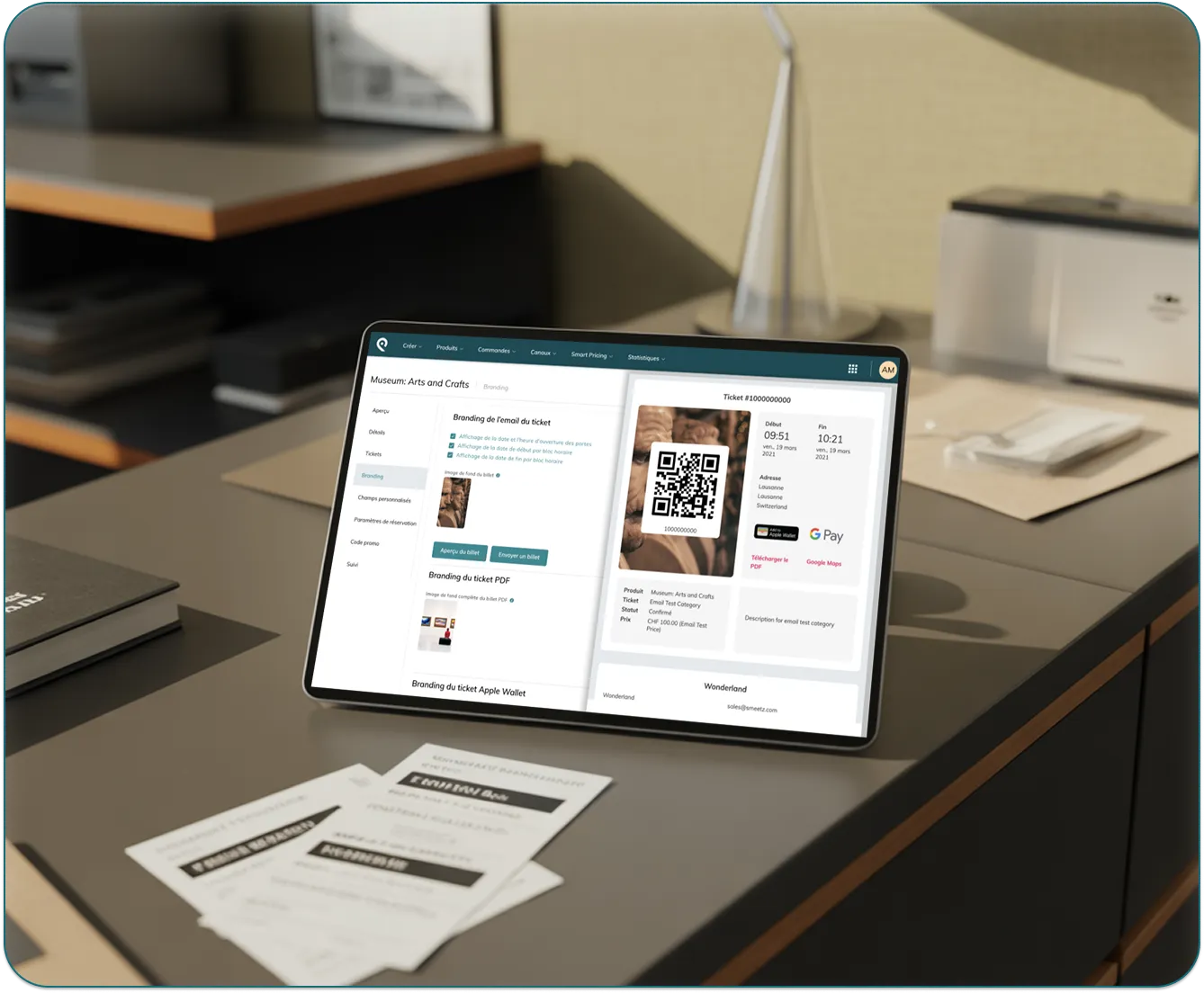 Tablet showing ticket branding and details including QR code, dates, location, and payment options on a desk.