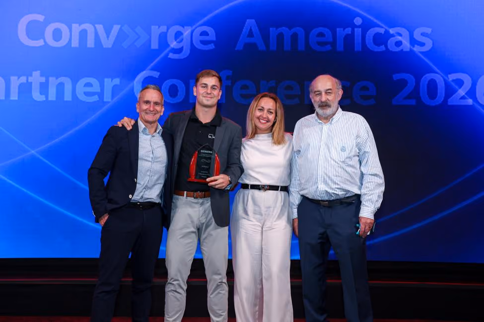 Four people standing and smiling on stage at an awards event with a blue background screen.