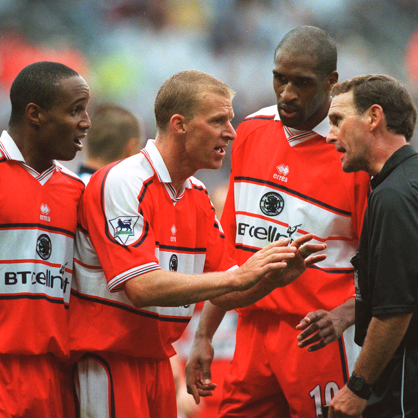 Robbie Mustoe, Paul Ince and Brian Deane in Middlesbrough kits talking with a referee during a match.