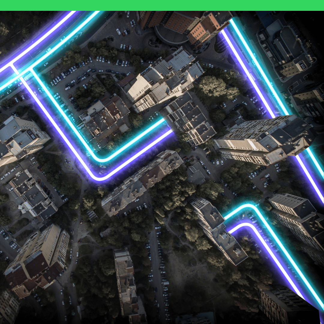 Aerial city view of buildings and streets highlighted with glowing blue and purple neon lines.