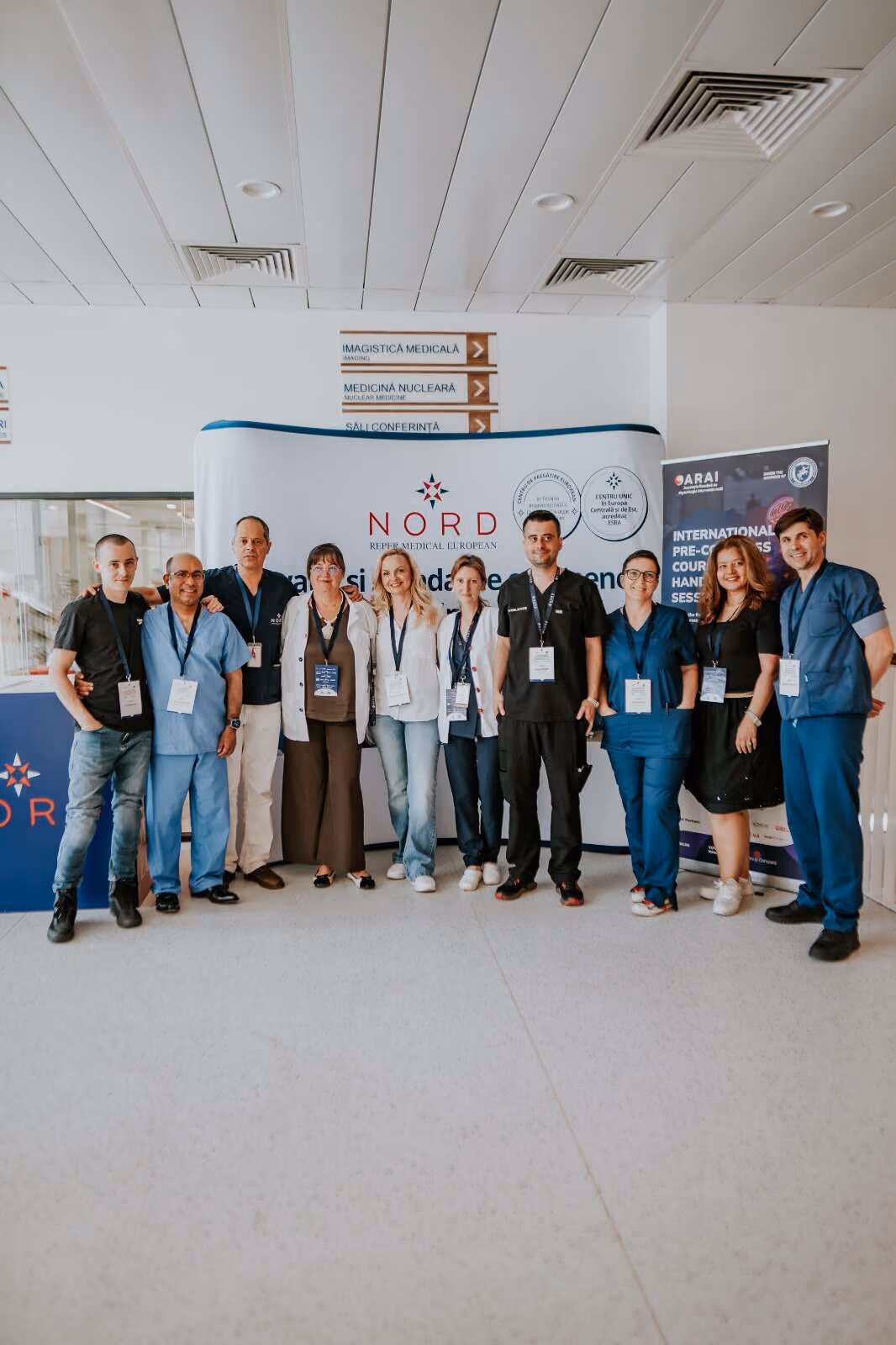 Un grup de zece profesioniști medicali stând în picioare în fața unui banner NORD într-un spațiu interior.