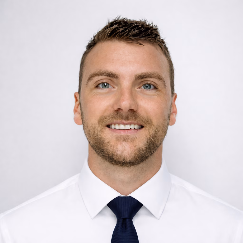 Portrait d'un homme souriant portant une chemise blanche et une cravate bleue marine.