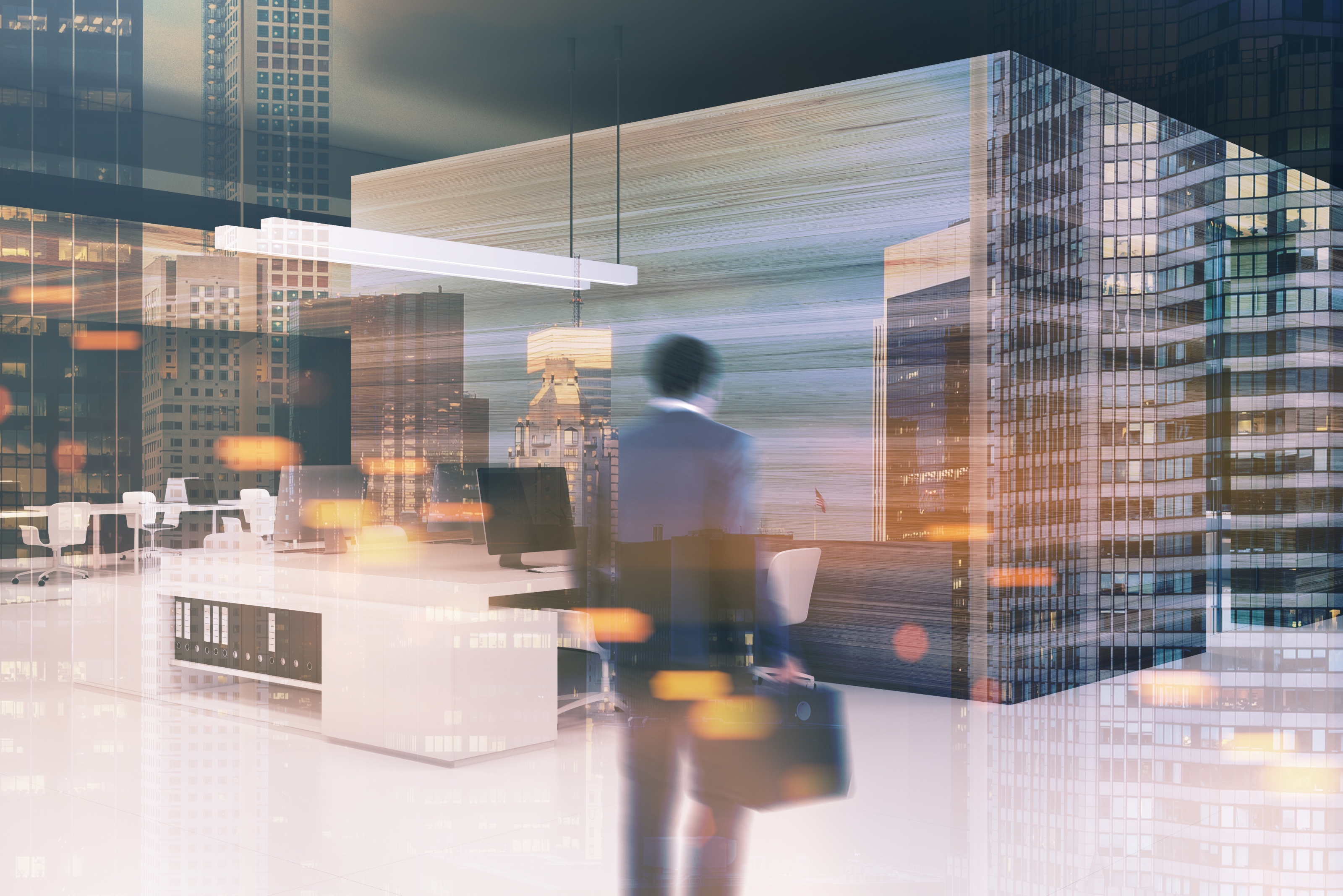 Blurred figure of a person holding a briefcase standing in a modern office with desks, chairs, and computers, overlaid with reflections of tall city buildings at dusk.